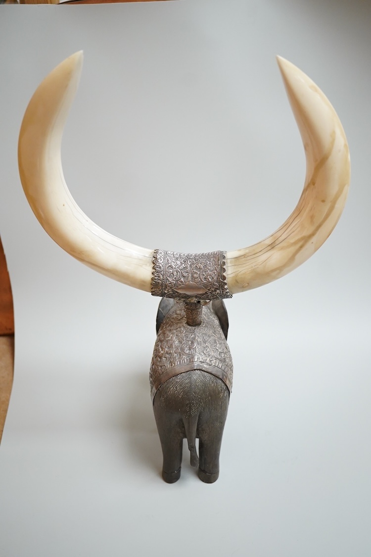 A late 19th century Indian white metal mounted carved hardwood model of an elephant, surmounted by a pair of removeable warthog tusks, overall height 40cm